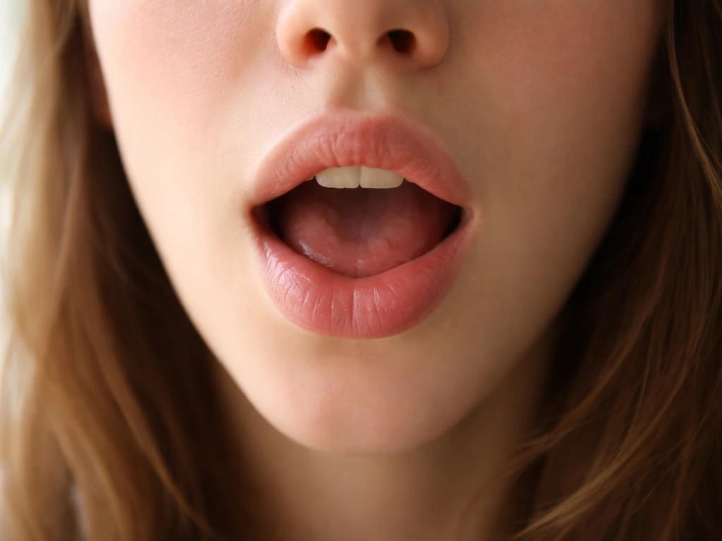 Close-up of a relaxed mouth showing tongue and lip position for the “tan” /æ/ sound
